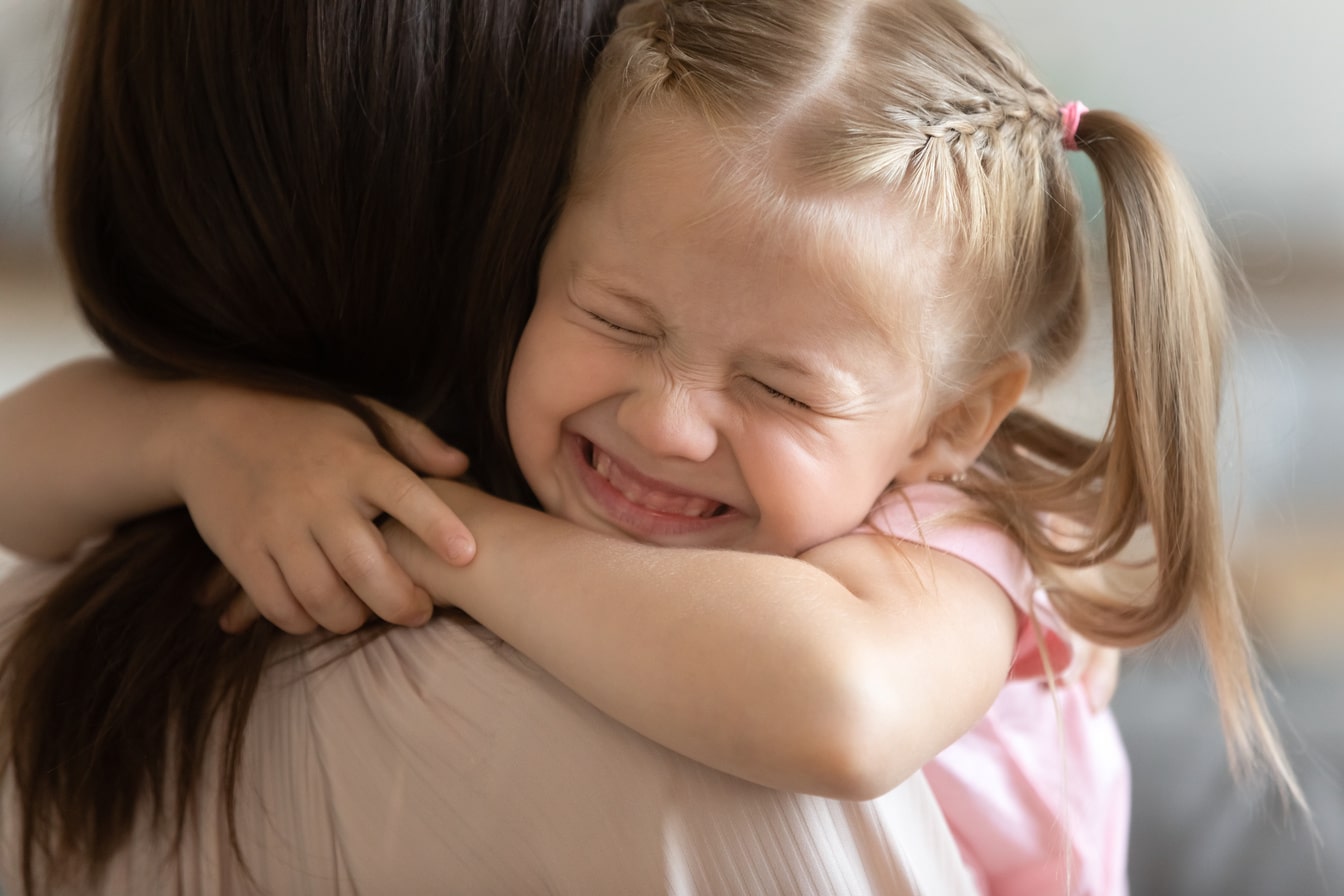 A young girl hugging her mother.