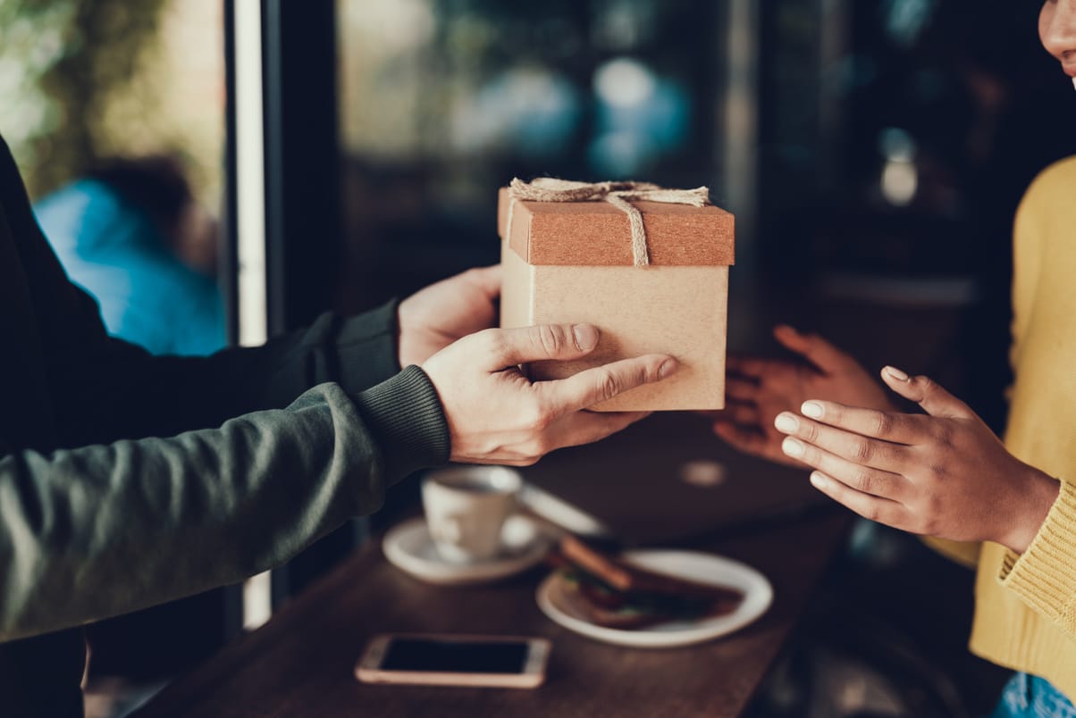 a man giving a small gift to a woman