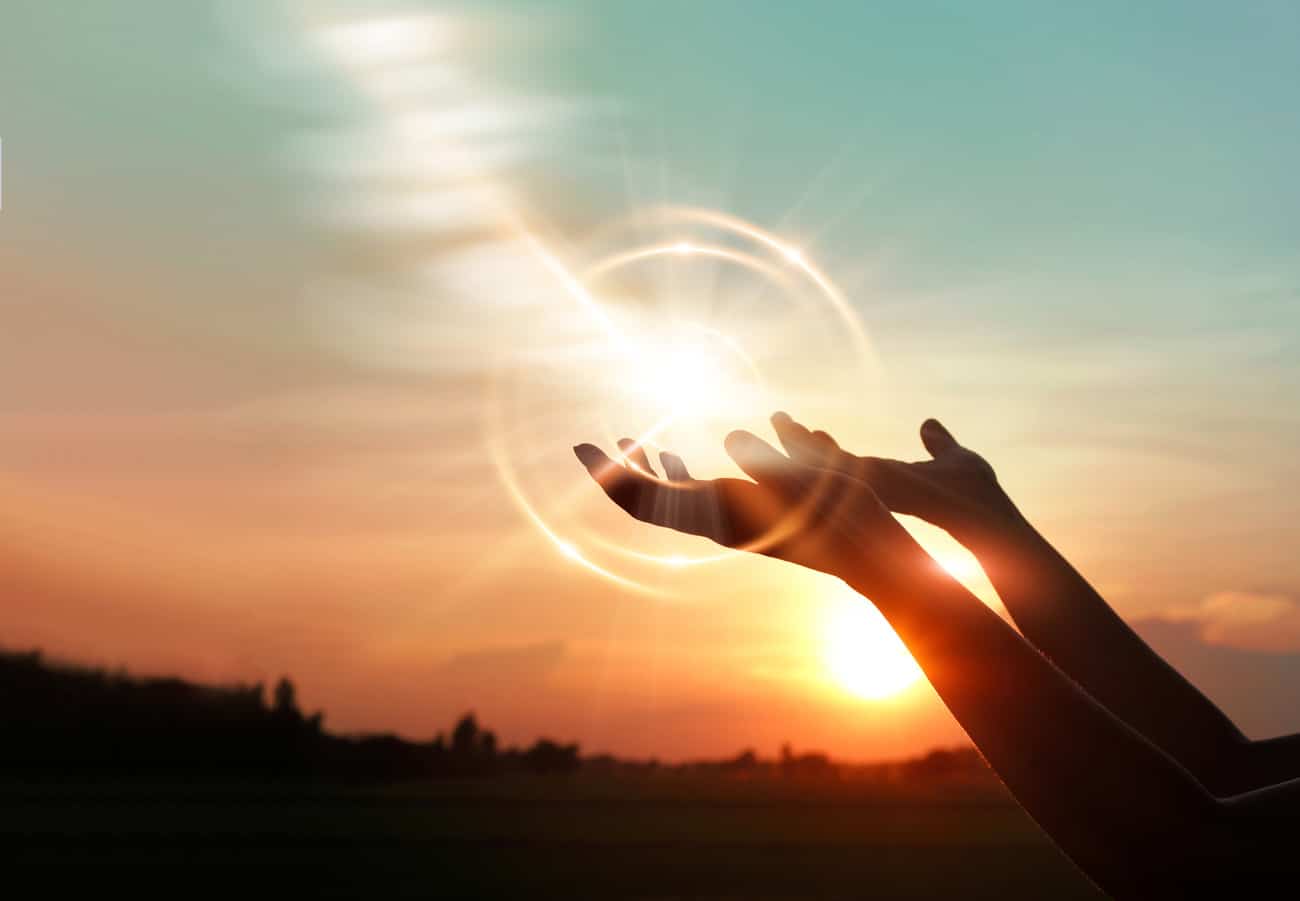 Hands outstretched in prayer towards the sun.