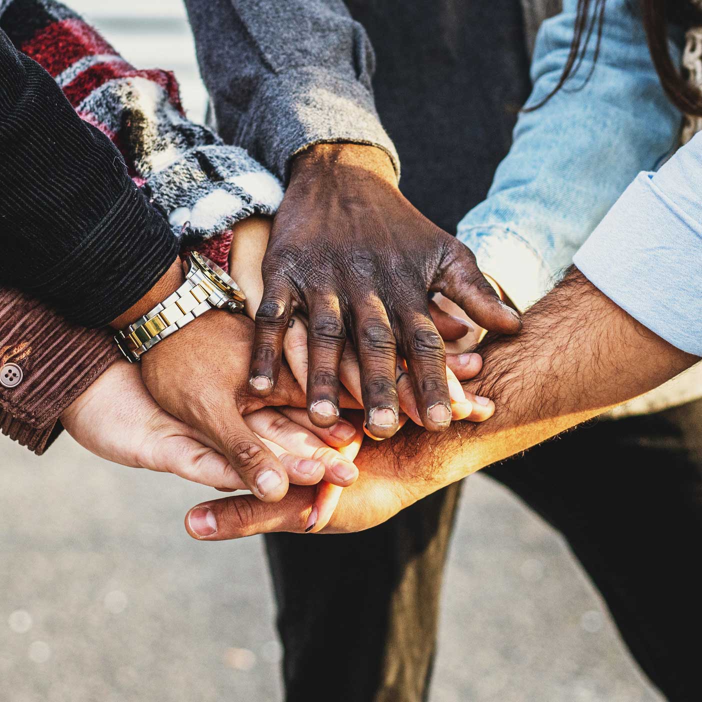 A group of diverse people putting their hands together in a circle.
