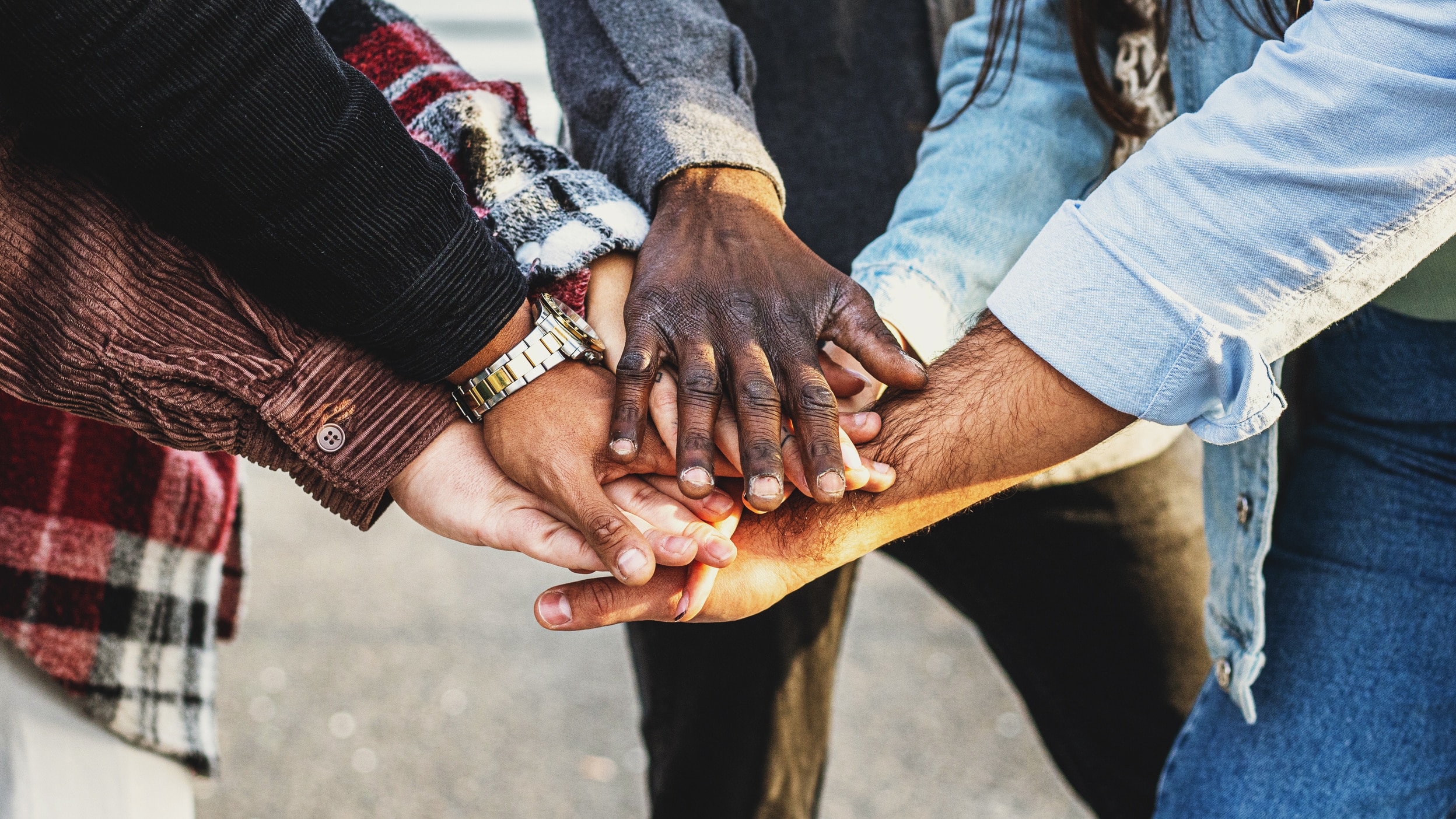 A group of diverse people putting their hands together in a circle.